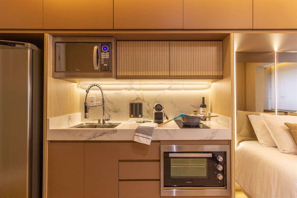 Cozinha com bancada de mármore, micro-ondas, forno, cooktop e cafeteira